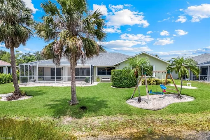Rear view of property with a playground, a yard, stucco siding, and a lanai