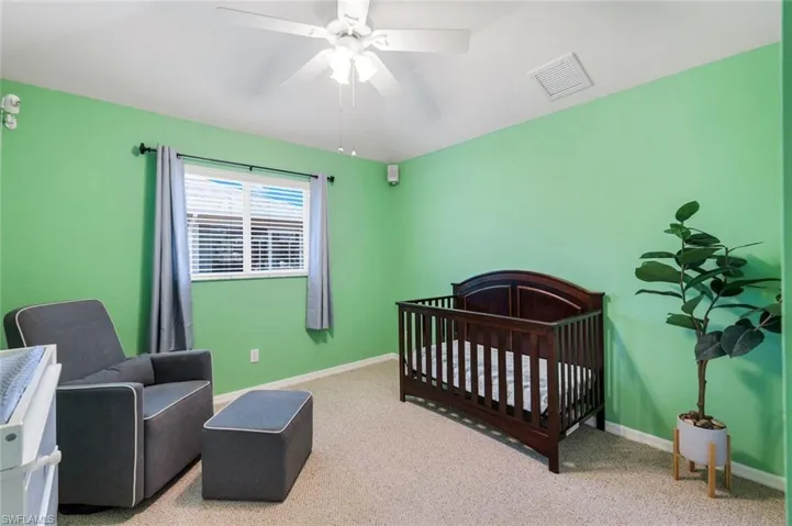 Bedroom featuring carpet, a nursery area, and a ceiling fan