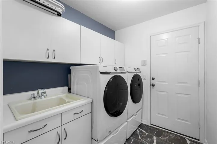 Laundry area with washing machine and clothes dryer, cabinet space, and dark marble finish floors