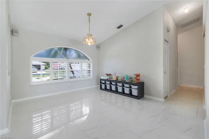 Spare room featuring marble look tiles and a chandelier