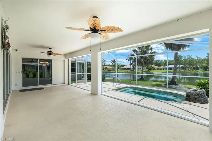 Outdoor pool featuring a water view, ceiling fan, a patio, and glass enclosure