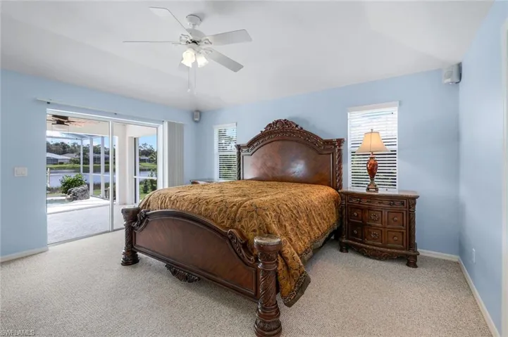 Carpeted bedroom featuring access to exterior, multiple windows, and ceiling fan
