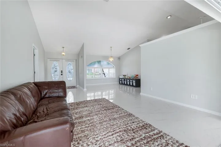 Living area with marble tiled flooring, lofted ceiling, a chandelier, and recessed lighting