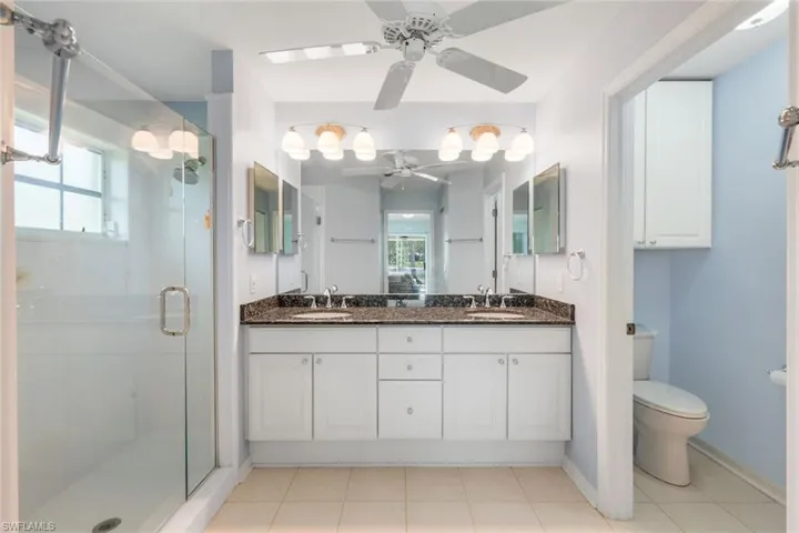 Bathroom featuring a ceiling fan, a stall shower, double vanity, and tile patterned floors
