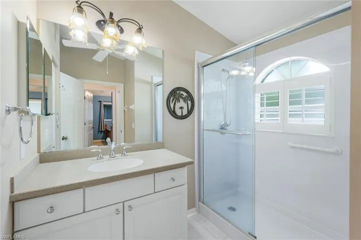 Full bath with a stall shower, vanity, tile patterned floors, and a chandelier