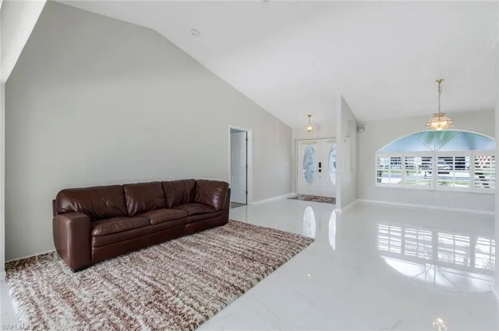 Living area featuring marble finish flooring and high vaulted ceiling