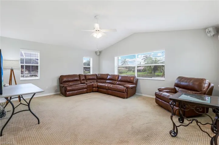 Carpeted living area featuring ceiling fan and lofted ceiling