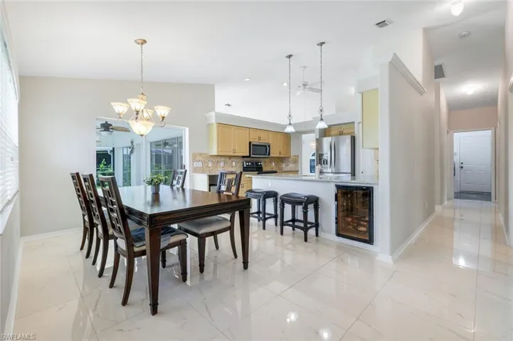Dining room featuring a chandelier, light marble finish floors, a ceiling fan, and wine cooler