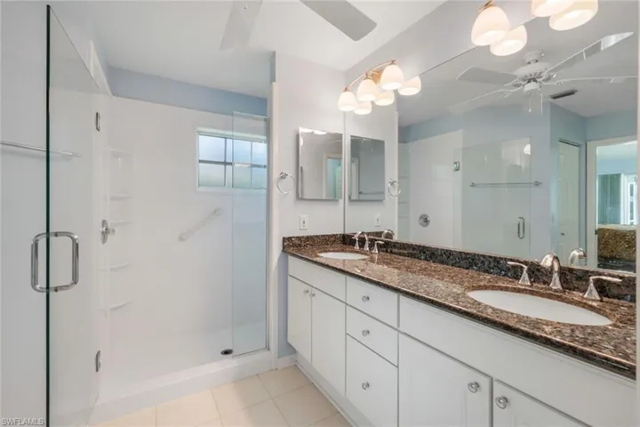 Bathroom with ceiling fan, a shower stall, double vanity, and tile patterned floors