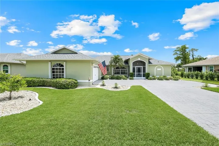 Ranch-style house with stucco siding, a front yard, decorative driveway, and an attached garage