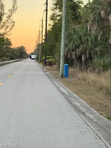 View of asphalt street with curbs and view of wooded area