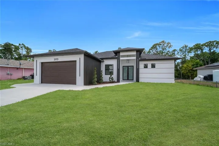 Prairie-style house featuring fence, concrete driveway, a front lawn, and a garage