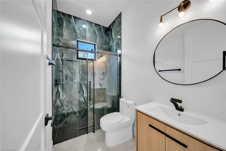 Full bathroom with tile patterned floors, vanity, toilet, and a marble finish shower