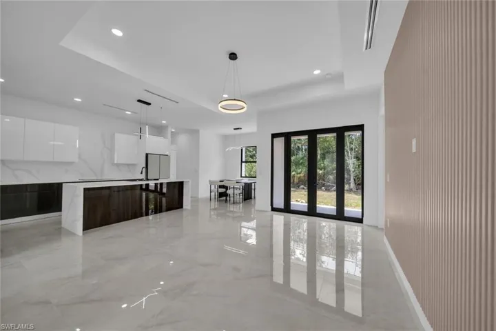 Unfurnished living room featuring recessed lighting, a tray ceiling, a high ceiling, and marble finish floor