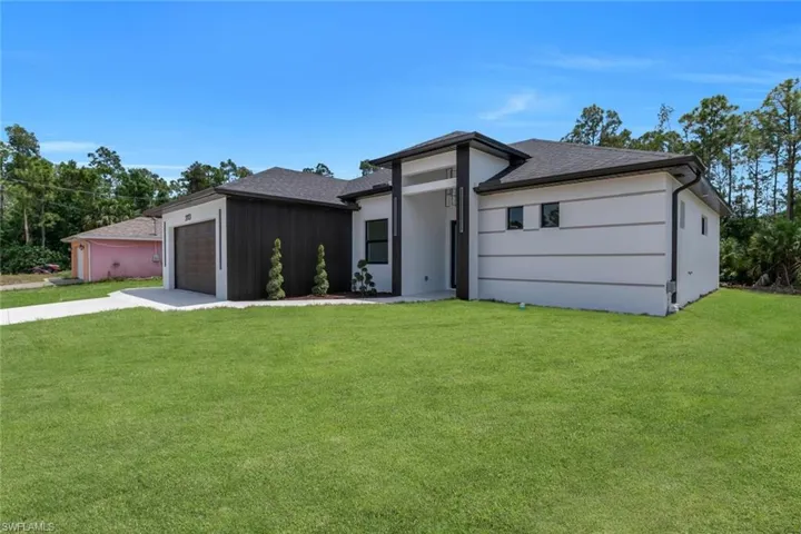 Prairie-style house featuring a garage, a shingled roof, a front lawn, and driveway