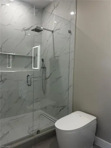 Bathroom featuring toilet and a marble finish shower
