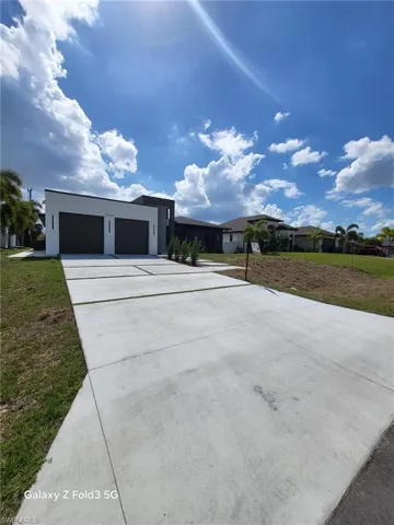 View of front of house featuring a front yard, a garage, driveway, and stucco siding