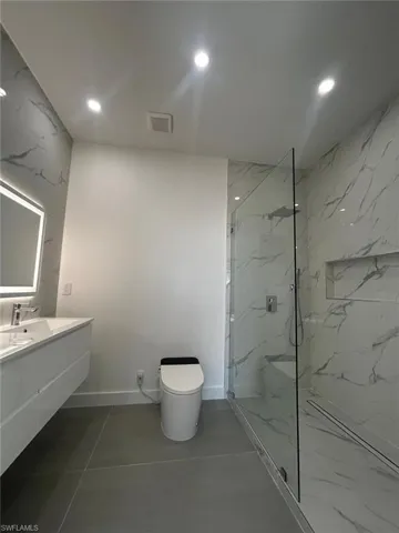 Full bath featuring vanity, recessed lighting, and a marble finish shower