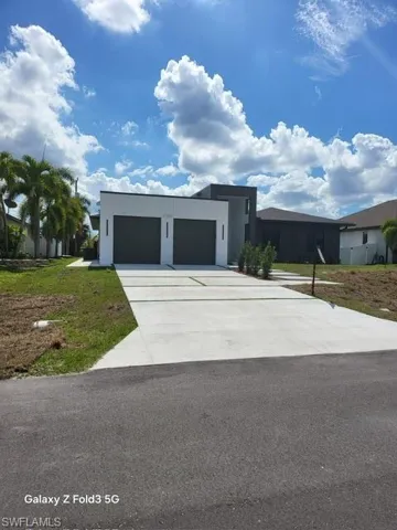 Contemporary home featuring a garage, concrete driveway, a front lawn, and stucco siding