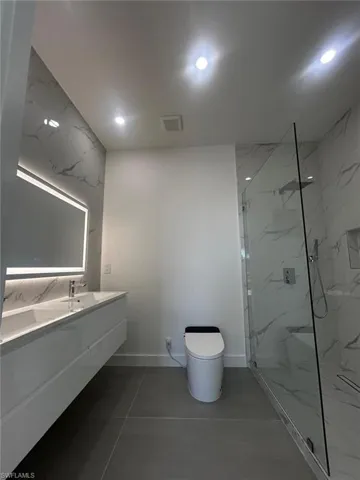 Bathroom featuring double vanity, a marble finish shower, and recessed lighting