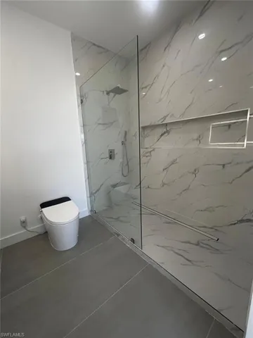 Full bath with a marble finish shower