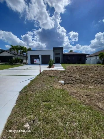 View of front of house with driveway, a front yard, and stucco siding