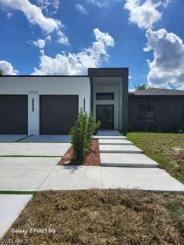 Contemporary home with stucco siding, a garage, and concrete driveway