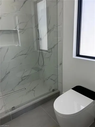 Full bathroom with toilet and a marble finish shower