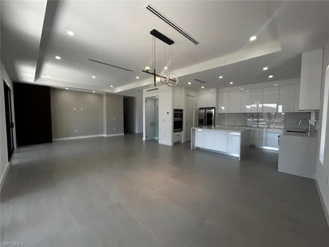 Kitchen with open floor plan, a kitchen island, white cabinetry, decorative backsplash, and stainless steel appliances