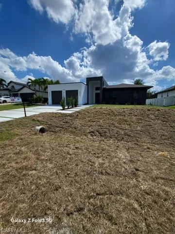 View of front facade featuring concrete driveway, a garage, and a front yard