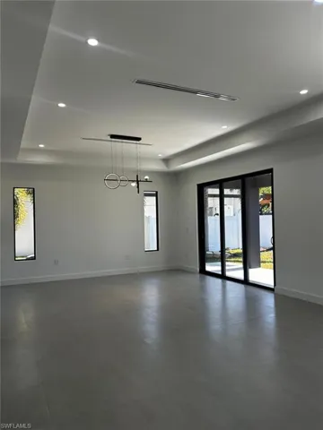 Unfurnished room with a raised ceiling, recessed lighting, and concrete floors