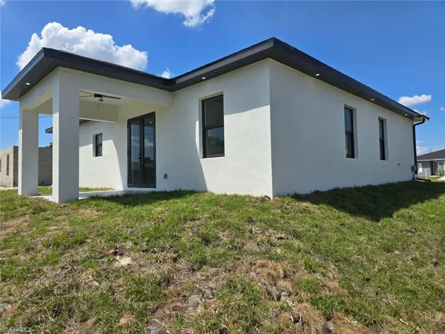 Rear view of house featuring stucco siding, french doors, and a yard
