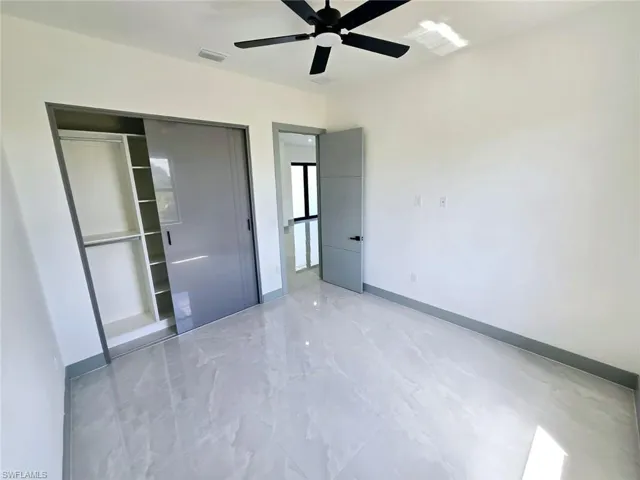 Unfurnished bedroom featuring a closet, a ceiling fan, marble finish floor, baseboards, and visible vents