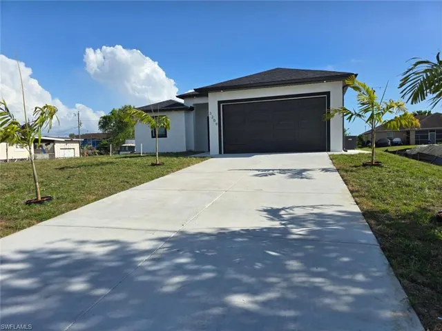 View of front of property with driveway, an attached garage, a front lawn, and stucco siding