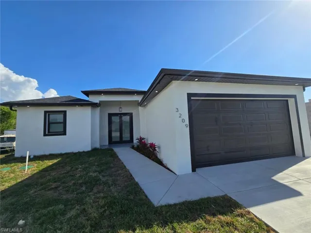 View of front of house with french doors, a front lawn, stucco siding, and an attached garage