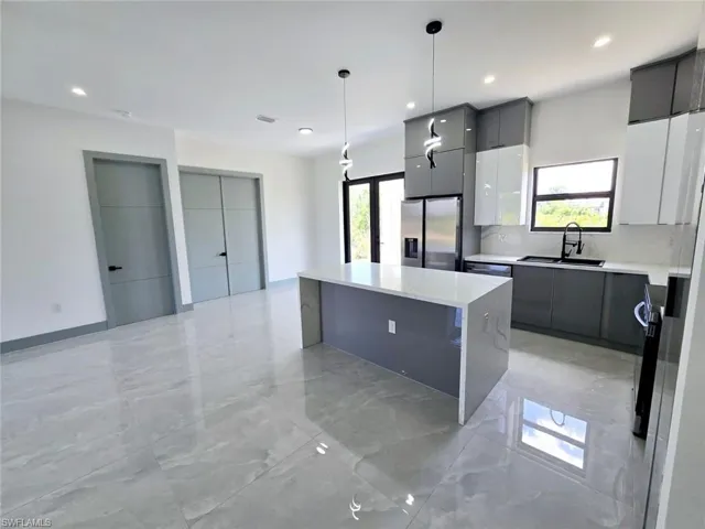 Kitchen with modern cabinets, a sink, stainless steel fridge, and a kitchen island