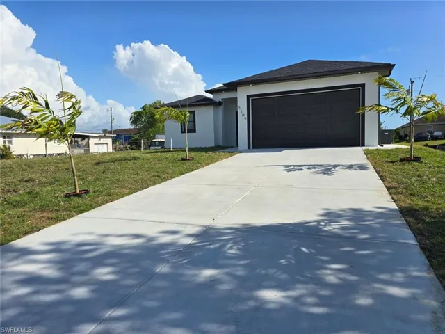View of front of house featuring a front lawn, concrete driveway, stucco siding, and an attached garage