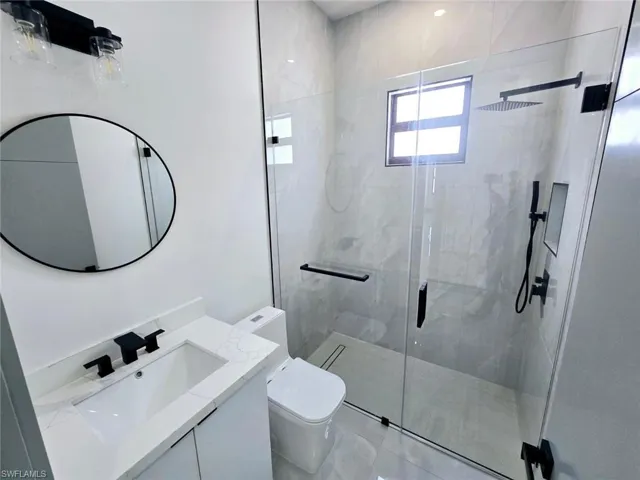 Bathroom featuring a stall shower, toilet, and vanity