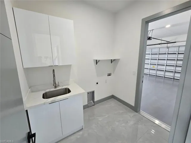 Laundry room featuring washer hookup, baseboards, a sink, hookup for an electric dryer, and cabinet space