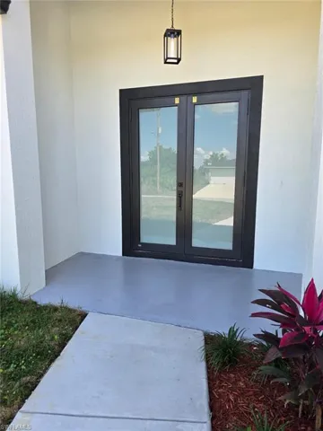 Doorway to property featuring french doors and stucco siding