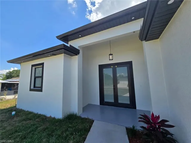 Doorway to property featuring stucco siding and french doors
