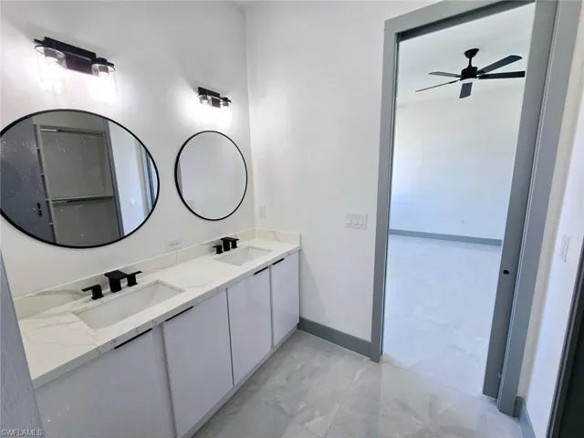 Full bathroom featuring a ceiling fan, a sink, double vanity, and baseboards