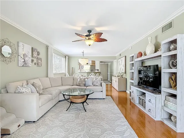 Living room featuring ceiling fan, ornamental molding, and light wood-type flooring
