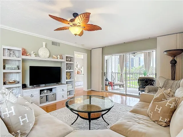 Living room featuring light wood finished floors, ceiling fan, and crown molding