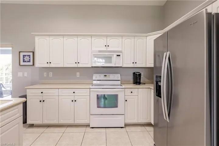 Kitchen featuring white cabinetry, white appliances, and light tile patterned floors