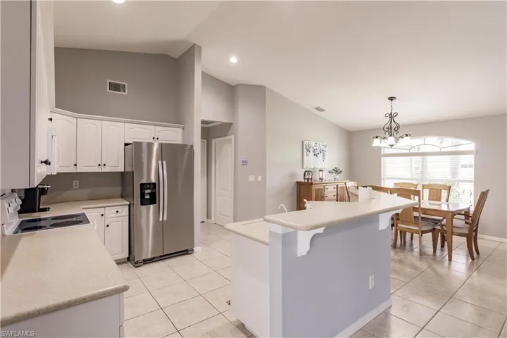 Kitchen with a chandelier, white cabinets, a kitchen island, decorative light fixtures, and stainless steel refrigerator with ice dispenser
