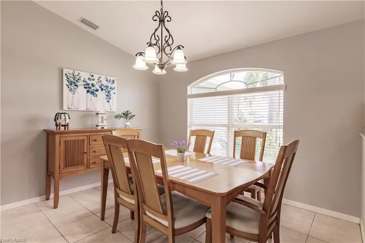 Dining room featuring light tile patterned floors, vaulted ceiling, and a chandelier