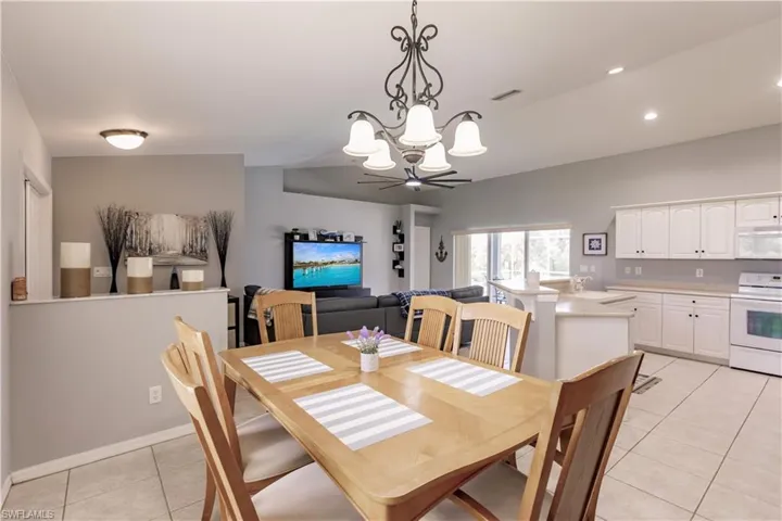 Tiled dining space with sink and ceiling fan with notable chandelier