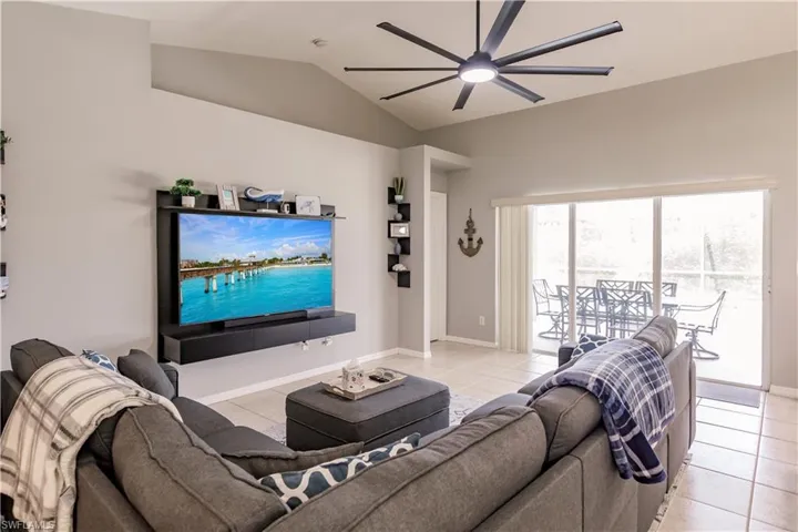 Living room featuring ceiling fan, vaulted ceiling, and light tile patterned floors