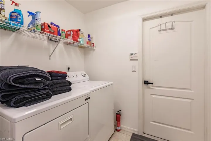 Washroom featuring light tile patterned flooring and washer and dryer
